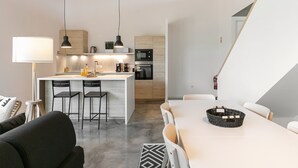 Ett modernt kök med en central köksö, barstolar och ett matbord med en flätad korg.