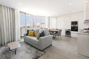 Un appartement moderne avec un canapé gris, une table à manger et un coin cuisine.