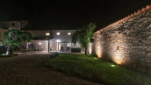 Een gebouw met stenen muren, een patio, buitenmeubels en een goed verlichte ingang.