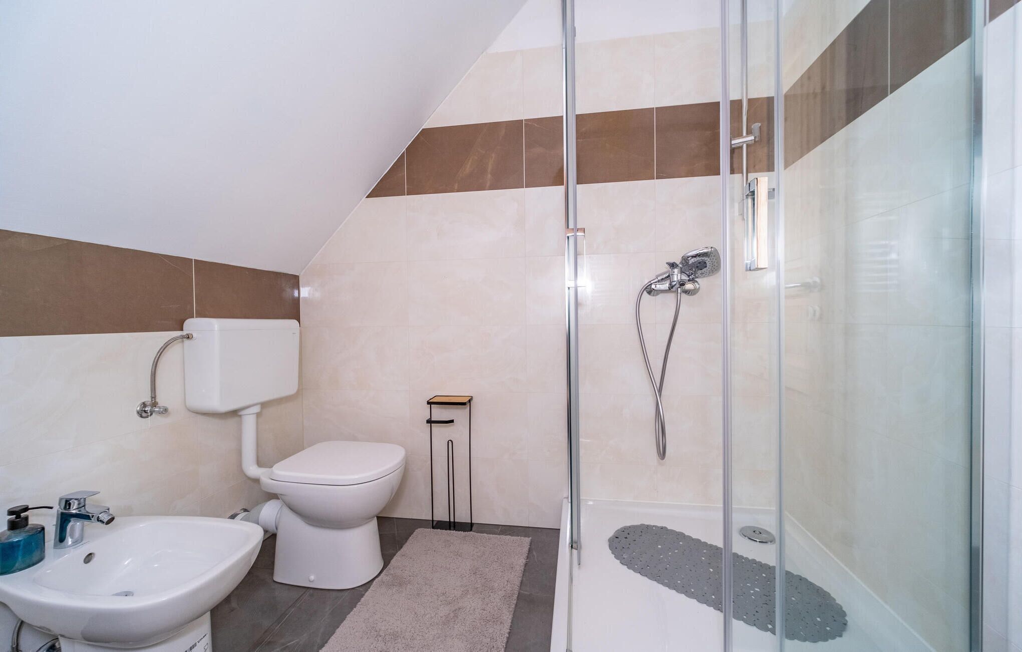 A modern bathroom with a toilet, bidet, and shower.
