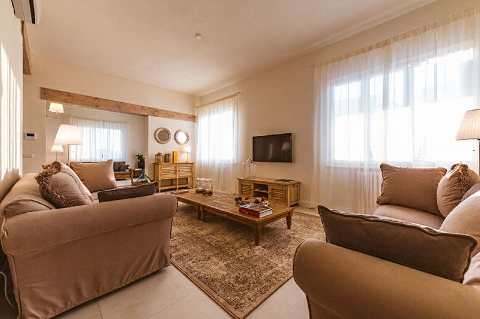 Una sala de estar con dos sofás, una mesa de centro, un televisor y un mueble de madera.