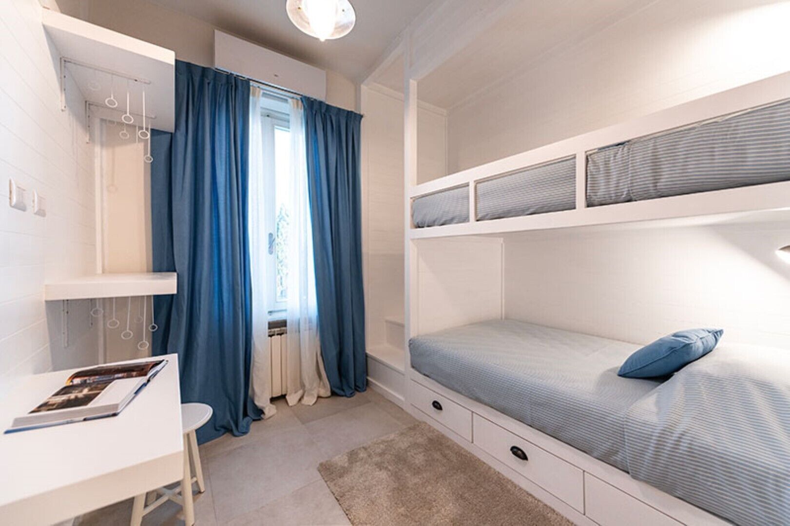 Ein Schlafzimmer mit Etagenbetten, einem Schreibtisch und einem Fenster mit Vorhängen.