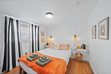 The bright and cheery Trapeze Nook room features a comfortable queen-size bed with soft lighting.