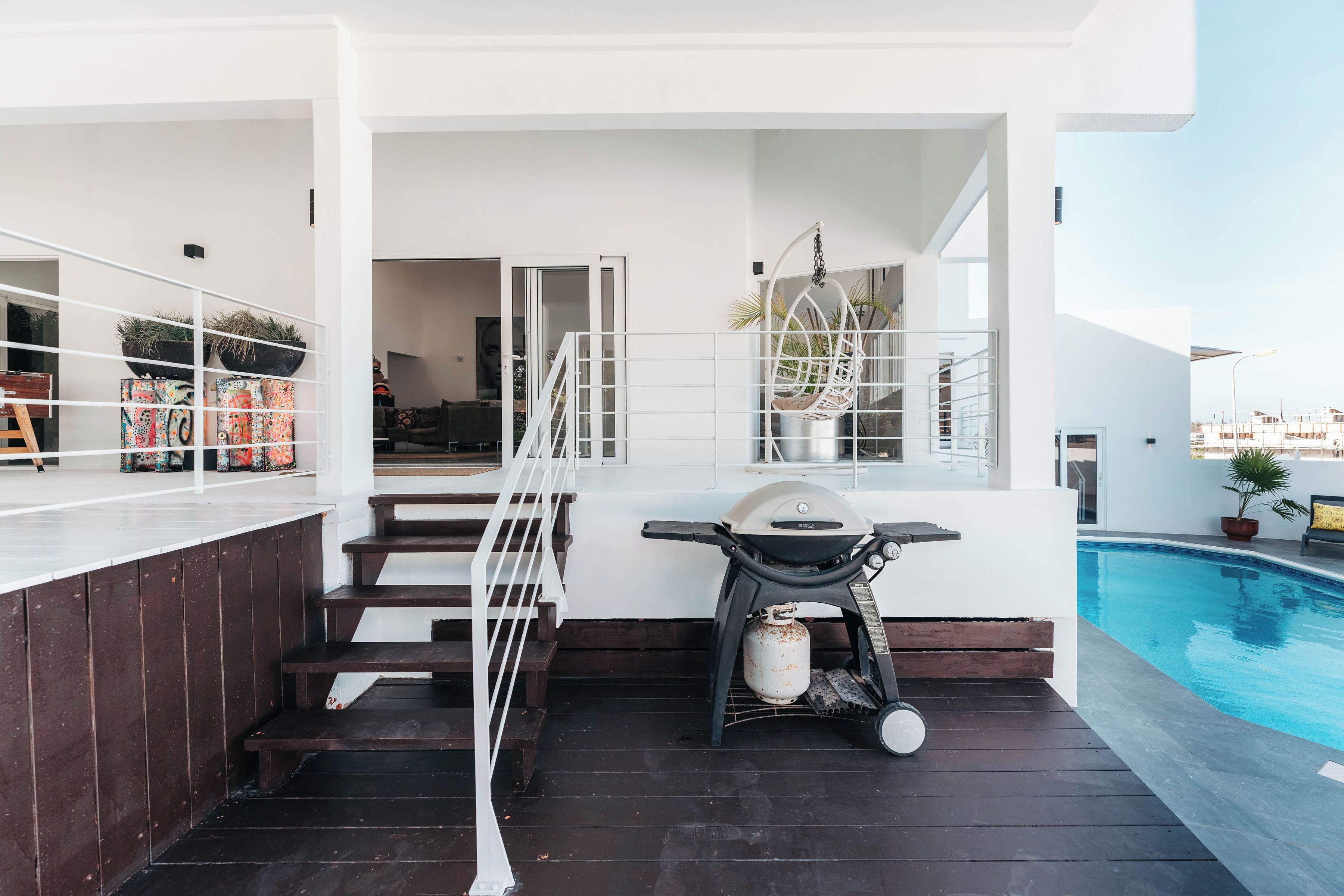 A poolside area with a grill, seating, and a staircase leading to an upper level.