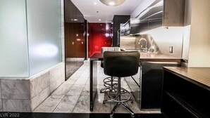 A modern kitchen with a bar area, a dining table, and a black chair.