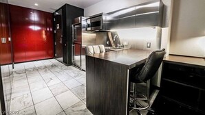 A modern kitchen with stainless steel appliances, a bar area, and a red wardrobe.