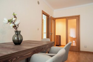 A dining area with a wooden table and chairs, a vase with flowers, and a door leading to another room.