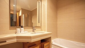 Un baño con lavamanos, espejo y bañera.
