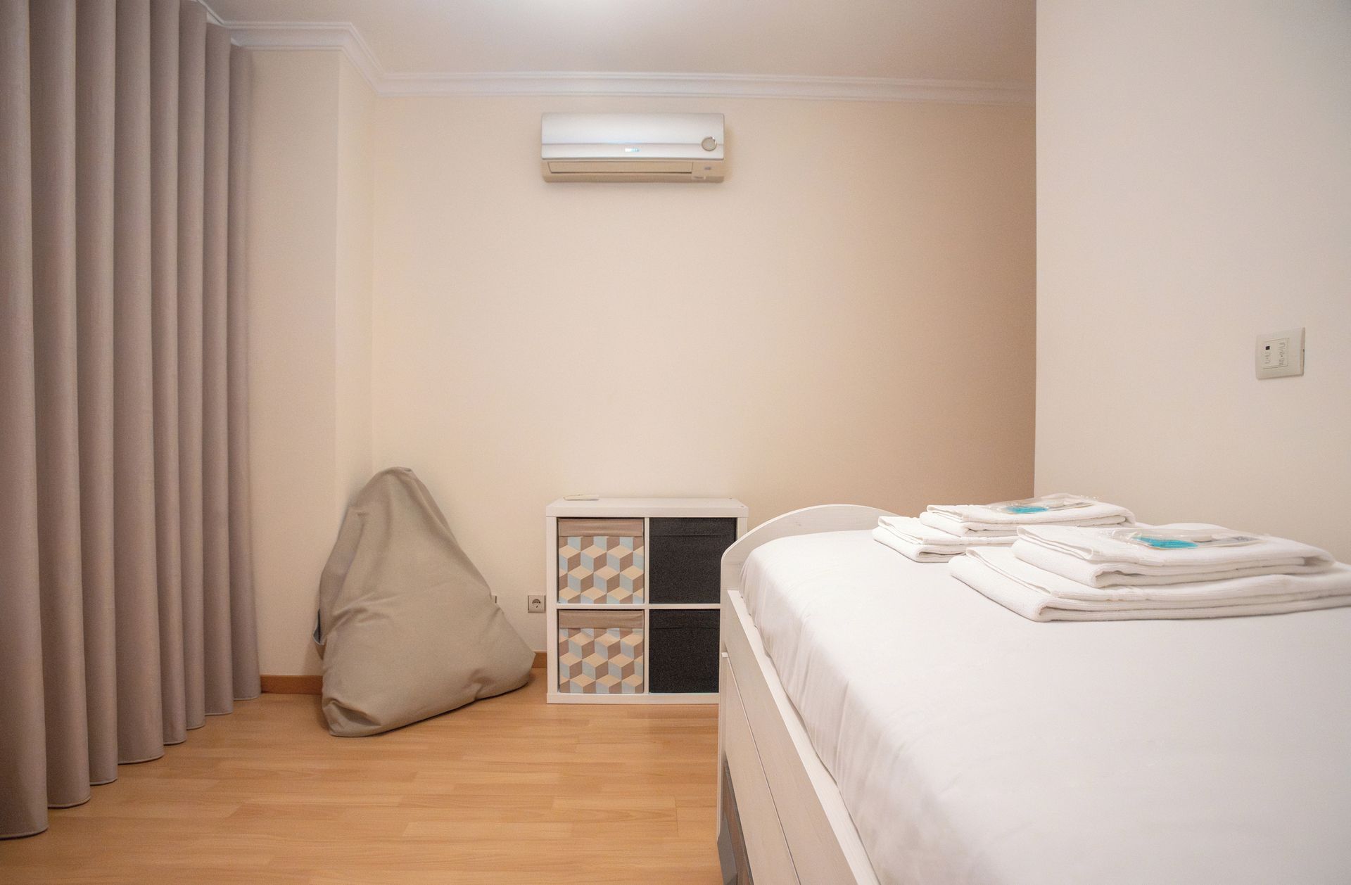Een slaapkamer met een bed, een kussen, een nachtkastje en een airconditioning.