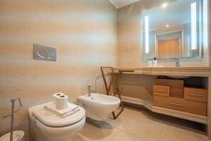 Un baño moderno con inodoro, bidé y tocador con cajones.
