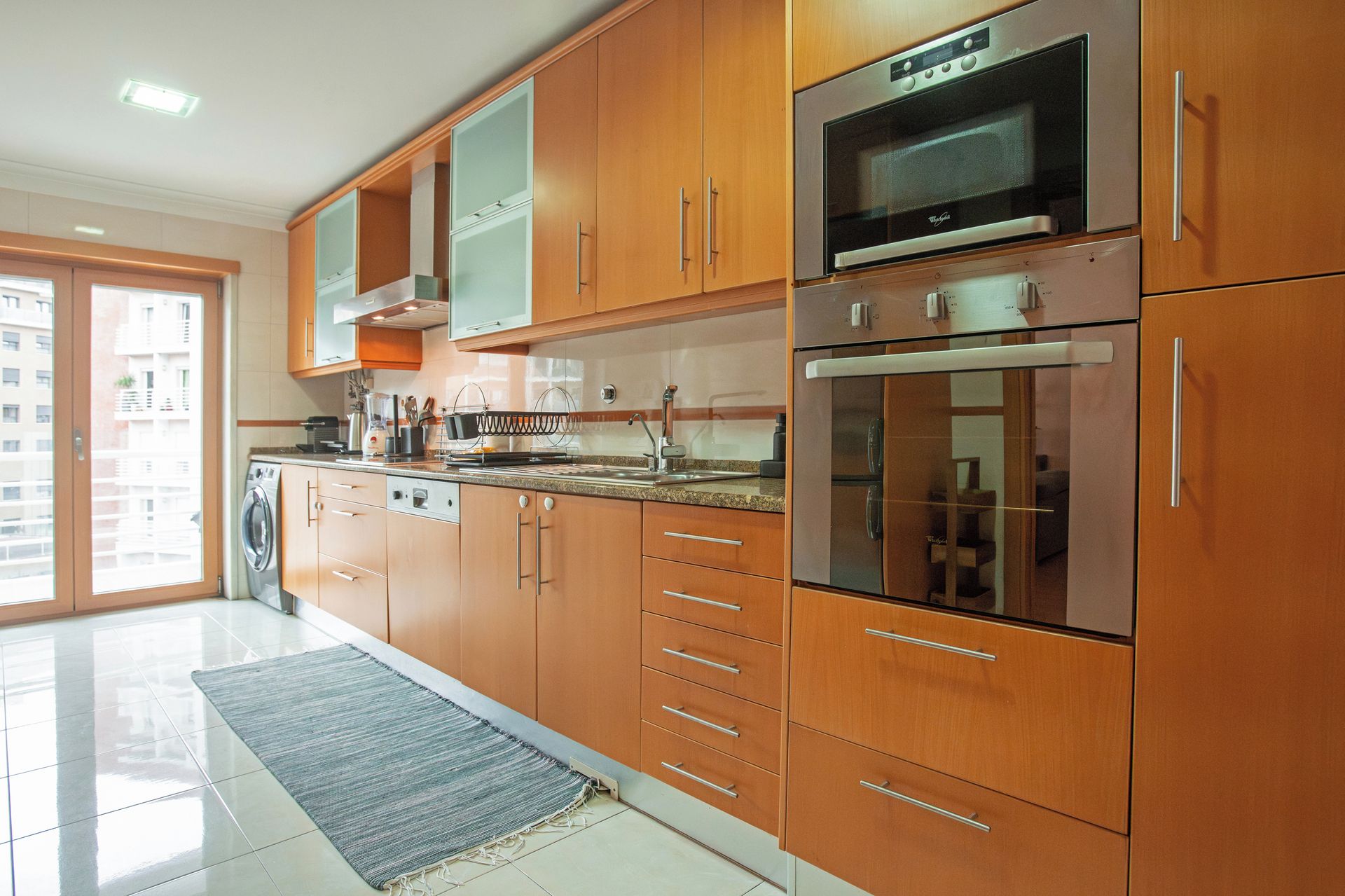 Une cuisine moderne dotée d’appareils électroménagers en acier inoxydable, de meubles en bois et d’une grande fenêtre.