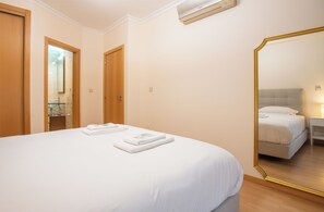 A hotel room with a bed, a large mirror, and a bathroom visible through an open door.