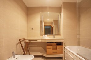 Un baño moderno con un espejo grande, un lavabo, un mueble de tocador con cajones y una bañera.