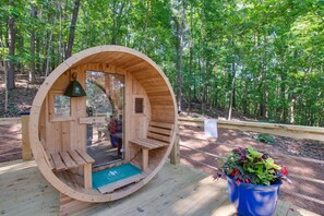 A wooden structure with a bench inside, surrounded by a forest.