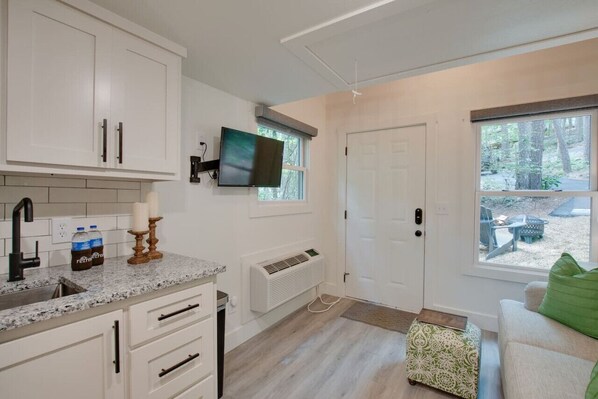 A modern kitchen with white cabinets, a granite countertop, a built-in stove, and a window with a view of the outdoors.