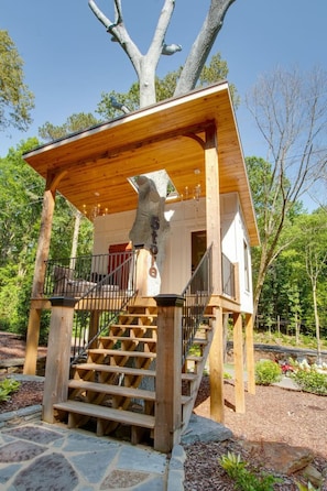 A wooden cabin with a stone staircase leading to a covered porch.