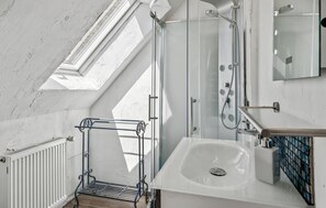 A modern bathroom with a skylight, a shower, a sink, and a metal rack. - Ferienwohnung Daniela (Rambin)
