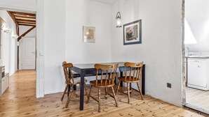 Zona pranzo con tavolo e sedie in legno, un lampadario e quadri appesi al muro.