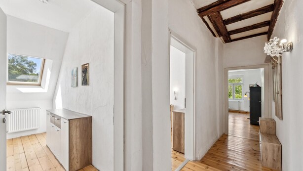 Una cucina moderna con mobili in legno, un piano di lavoro bianco e un lucernario.