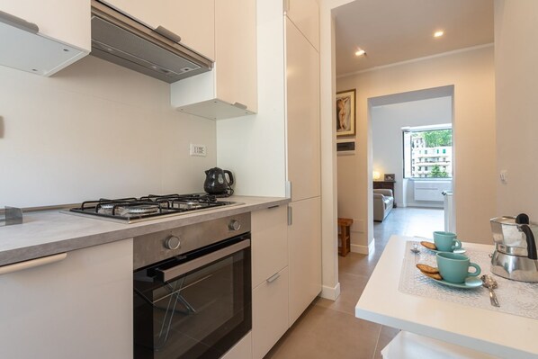 A modern kitchen with a gas stove, oven, and a coffee maker on the counter. - Trastevere at heart.. (Roma)