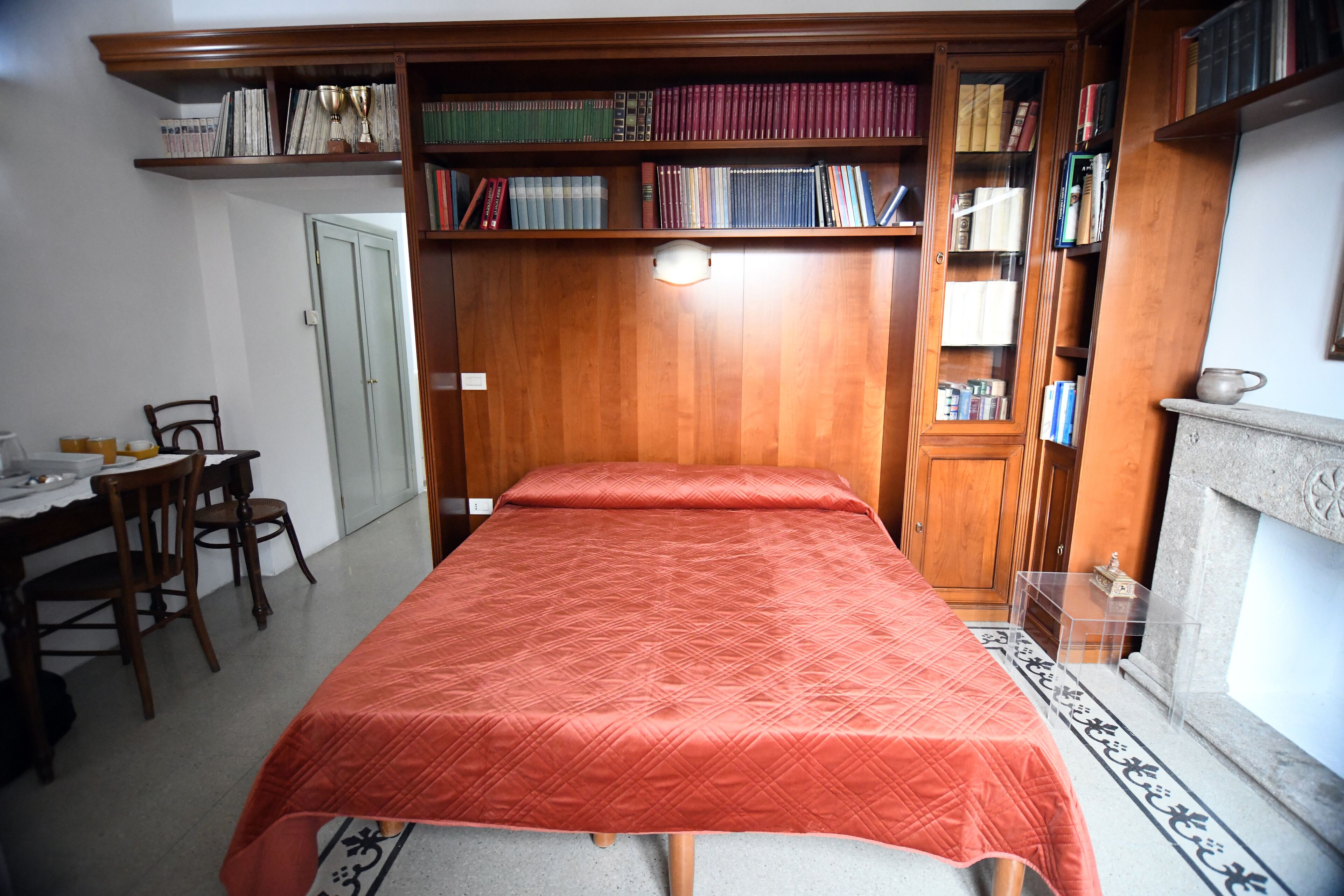 A bedroom with a bed, wooden bookshelves, a desk, and a chair.