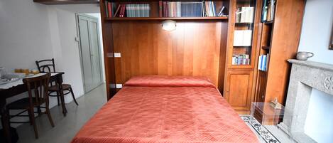 Un dormitorio con cama, estanterías de madera, un escritorio y una silla.