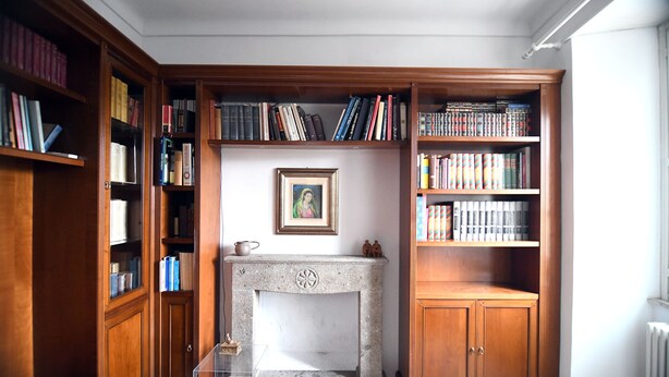 A library with bookshelves, a fireplace, and a framed picture on the wall. - Domo Peonia Bianca (Nuoro)