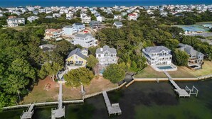 An aerial view of a coastal residential area with houses, a dock, and a body of water. - 1528 - Sound and Color - Spacious Soundfront Retreat w/ Stunning Sunsets (Corolla)