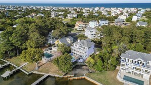 An aerial view of a coastal residential area with houses, a dock, and a body of water. - 1528 - Sound and Color - Spacious Soundfront Retreat w/ Stunning Sunsets (Corolla)