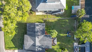 A residential area with a house featuring a sloped roof, a small deck, and a fenced yard.