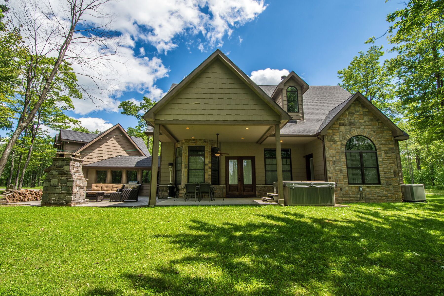 A two-story house with a stone foundation, a covered porch, and a well-maintained lawn.