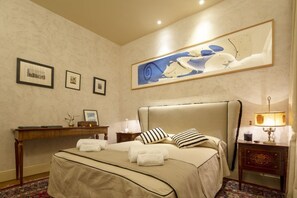 Une chambre d’hôtel avec un lit, un bureau, une lampe et un grand tableau abstrait accroché au mur.