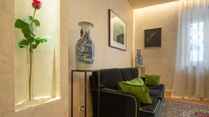 A living room with a sofa, a vase with a rose, and framed pictures on the wall. - Serragli Suite An in Santo Spirito Area (Firenze)