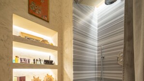A bathroom with a shower, shelves with toiletries, and a decorative wall. - Serragli Suite An in Santo Spirito Area (Firenze)