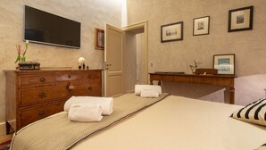 A bedroom with a bed, a dresser, a mirror, a flat-screen TV, and framed pictures on the wall. - Serragli Suite An in Santo Spirito Area (Firenze)