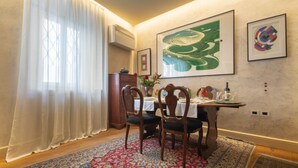 A dining area with a table set for four, chairs, a patterned rug, and artwork on the wall. - Serragli Suite An in Santo Spirito Area (Firenze)