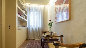 Un couloir comprenant un coin repas, une chaise en bois, un vase avec une rose et un tableau accroché au mur.