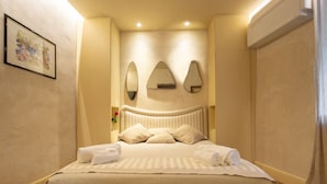 Un lit bien fait, avec une couvre-lit à rayures et des oreillers, un miroir fixé au mur et un tableau encadré accroché au mur.