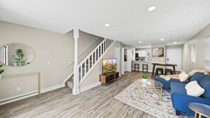 Stylish living space with a staircase, sofa, coffee table, and large mirror.