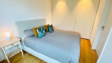 A bedroom with a bed, bedside table, and a wardrobe.