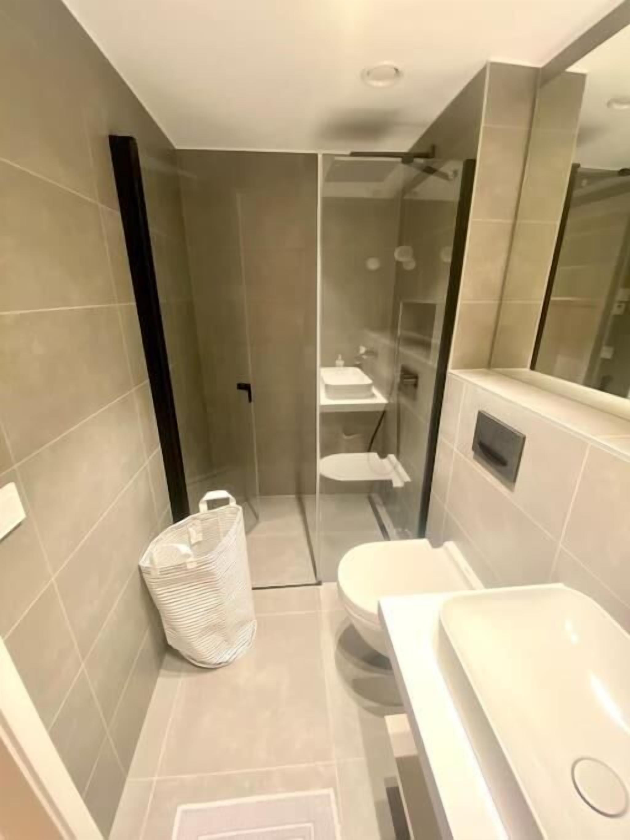 A modern bathroom with a glass-enclosed shower, a white sink, and a toilet.