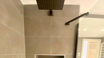 Un bagno moderno con doccia, un piccolo ripiano e un water.