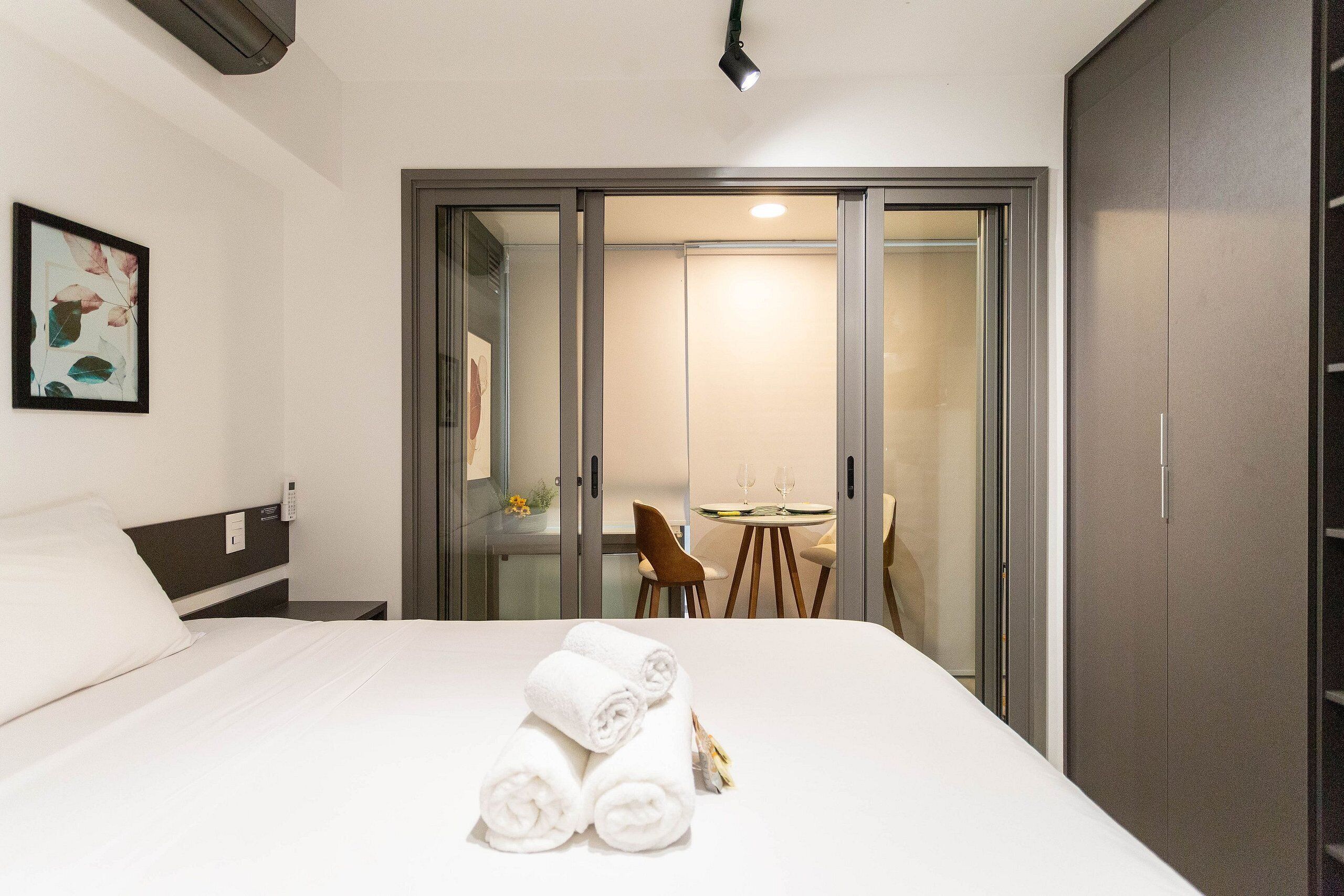 Et hotelværelse med seng, skrivebord, stol og spisebord med stole.