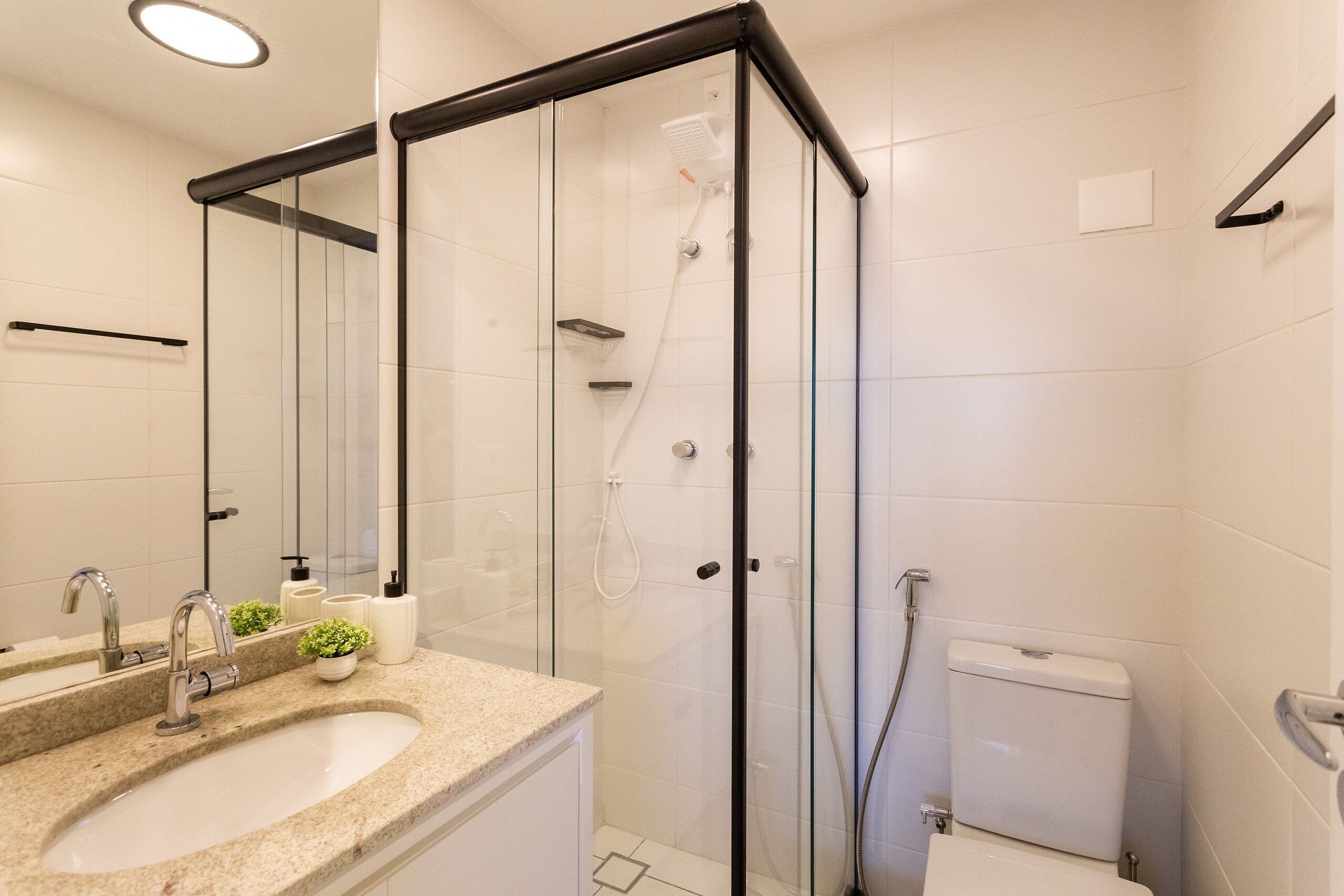 Un baño moderno con cabina de ducha de vidrio, un lavamanos con encimera de mármol y un inodoro.