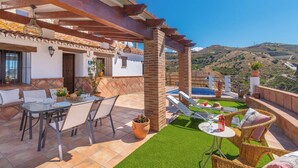 Un patio con mesa y sillas, una piscina pequeña y vistas a las colinas.