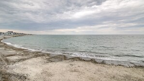 Una playa con arena dorada y un mar tranquilo bajo un cielo nublado.
