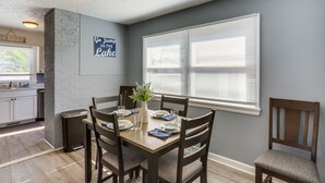 A dining area with a wooden table set for four, surrounded by dark wooden chairs. A ceiling fan is visible above, and a window with blinds is on the wall. - Dog-Friendly Port Clinton Home: Walk to Lake Erie! (Port Clinton)