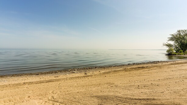 A beach with a sandy shore and calm water. - Dog-Friendly Port Clinton Home: Walk to Lake Erie! (Port Clinton)