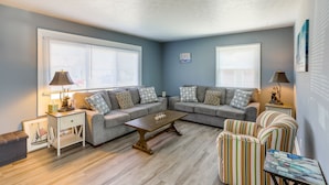A living room with two grey sofas, a wooden coffee table, striped armchairs, and a small side table with a lamp. - Dog-Friendly Port Clinton Home: Walk to Lake Erie! (Port Clinton)