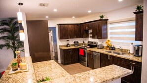 A modern kitchen with granite countertops, dark wood cabinets, stainless steel appliances, and a window with blinds. - Luxury Miami Villa/Nr Beach/Heated POOL/BBQ/Firepit/Games/Minigolf/Basketball (Miami)